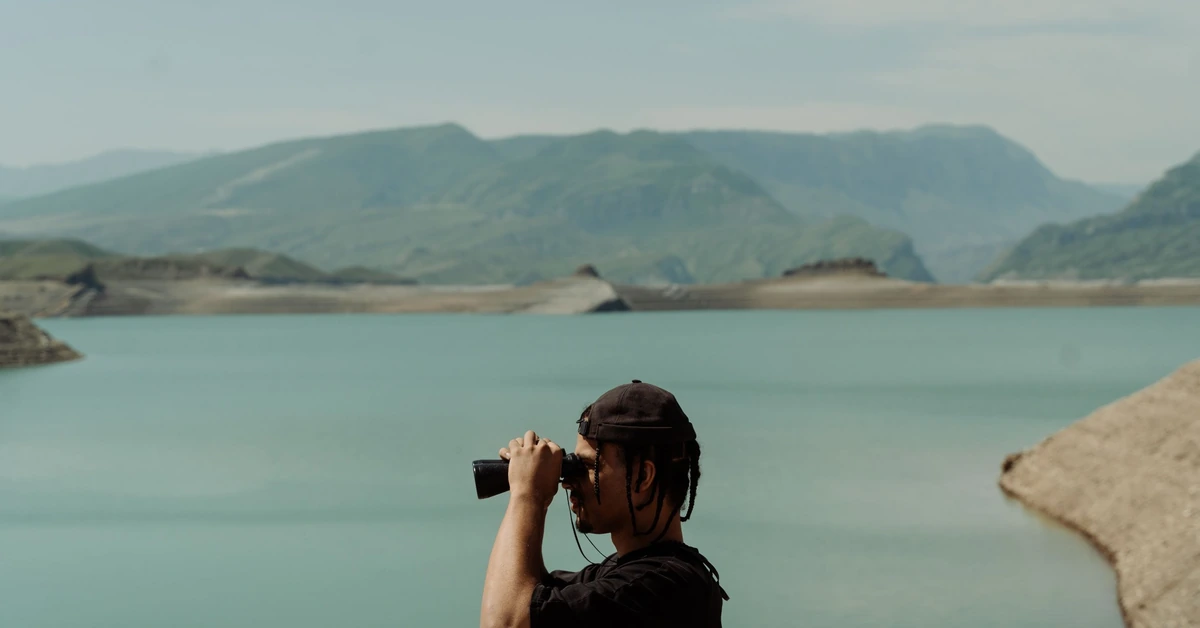Person using binoculars to scan a distant landscape, illustrating how marketers can watch for blog posts that are beginning to gain search visibility.