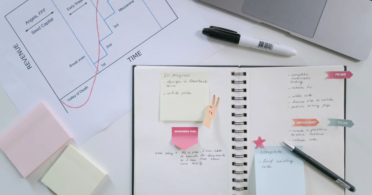 Notebook, planning chart, sticky notes, and laptop used to break a broad affiliate blog topic into focused supporting posts.