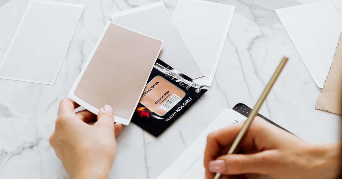 Person comparing several color samples while taking notes, representing the evaluation of affiliate products using consistent criteria