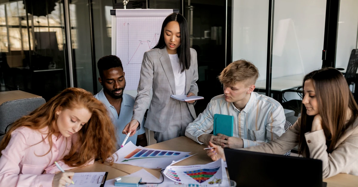 Diverse marketing team reviewing charts, notes, and a laptop together during a final content planning review
