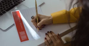 Woman writing in a content planner beside a laptop while organizing an affiliate blog publishing schedule.