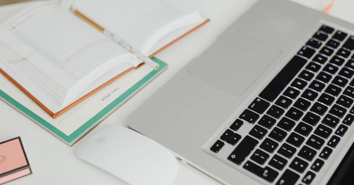 Laptop and open planner on a desk used to organize a weekly affiliate blog publishing schedule.