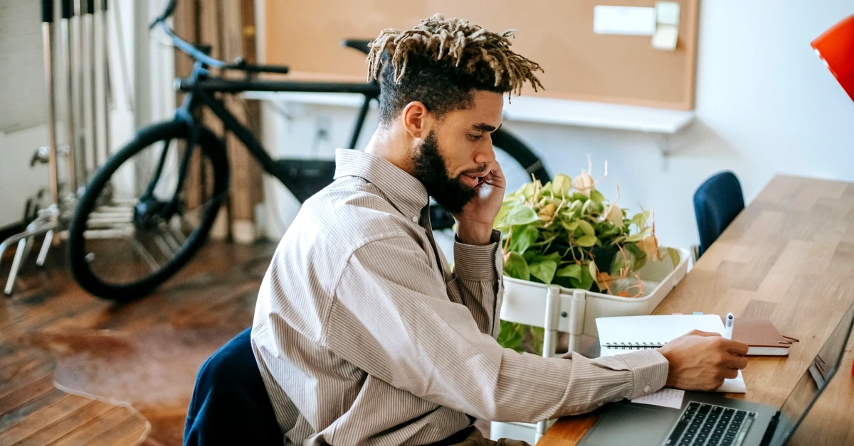 Affiliate marketer working on a laptop and taking notes while completing a focused content task
