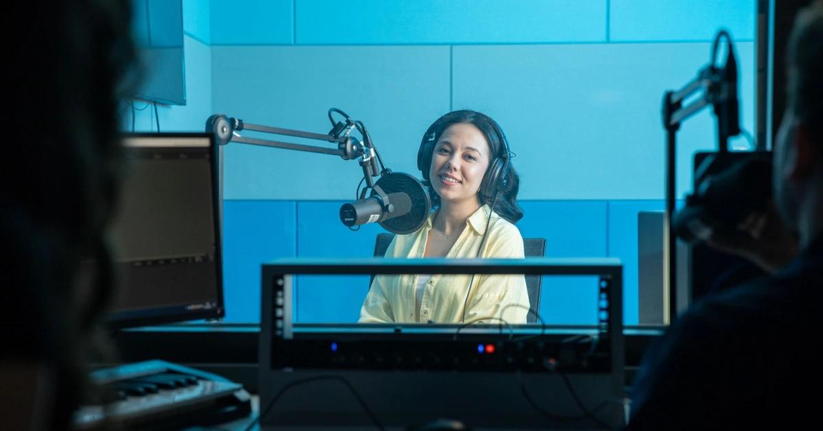 Podcast host speaking into a studio microphone, illustrating a timely broadcast sent directly to an audience.