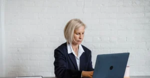 Businesswoman working on a laptop while reviewing documents at a desk