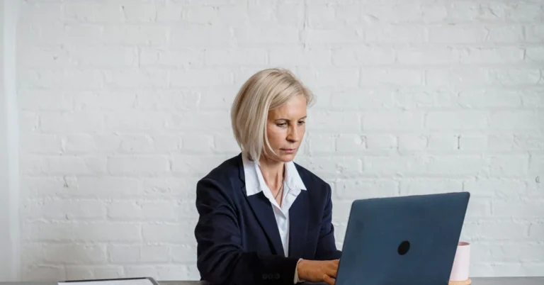 Businesswoman working on a laptop while reviewing documents at a desk