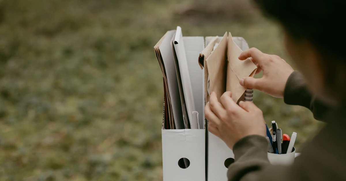 Hands sorting documents into separate folders, illustrating how tags and segments can organize affiliate email subscribers into useful groups.