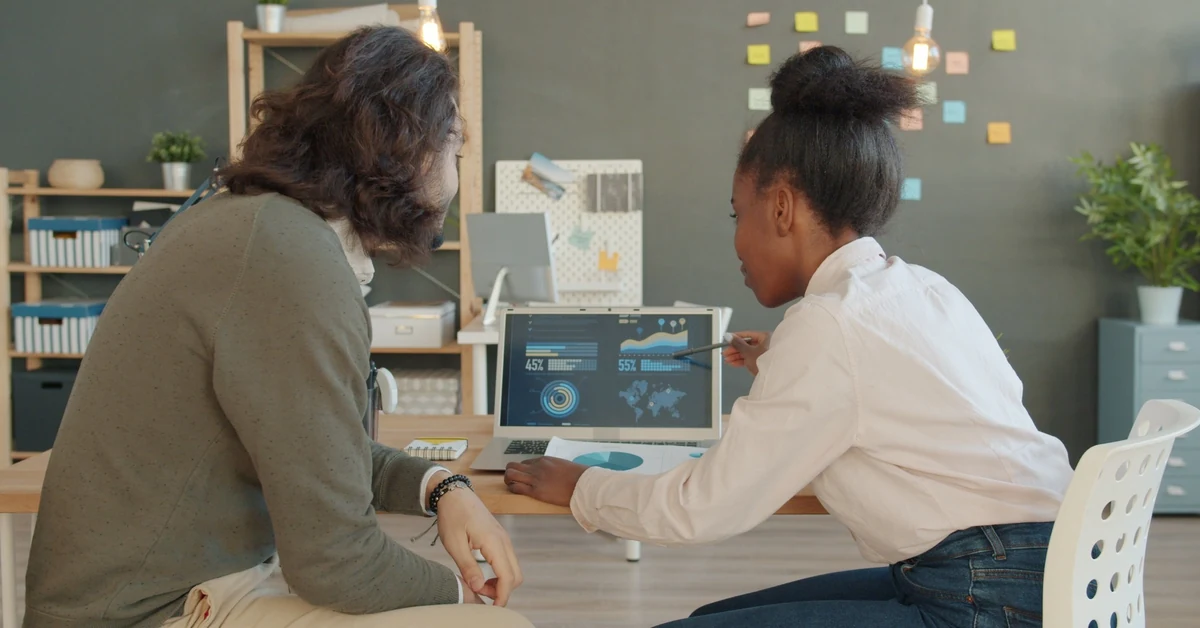 Two colleagues reviewing performance analytics on a laptop in an office