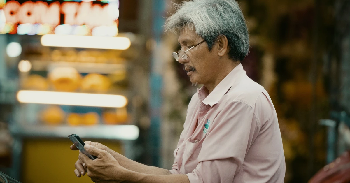 Older man using a smartphone in an urban setting, representing content distribution and audience reach.