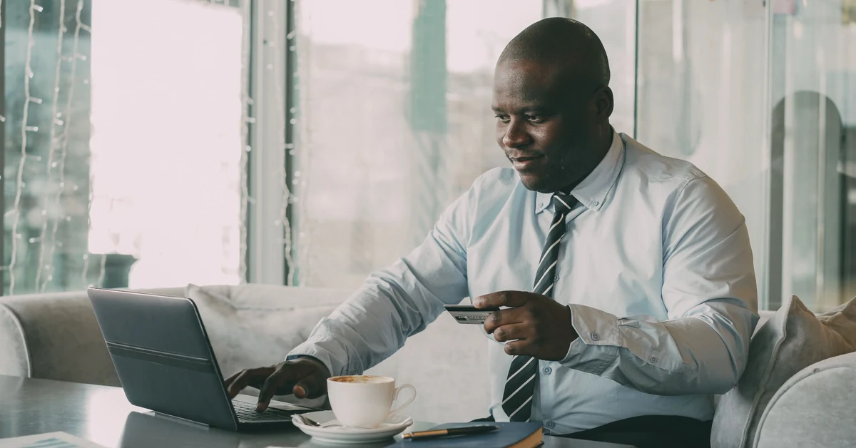 Businessman evaluating an online purchase with a laptop and credit card