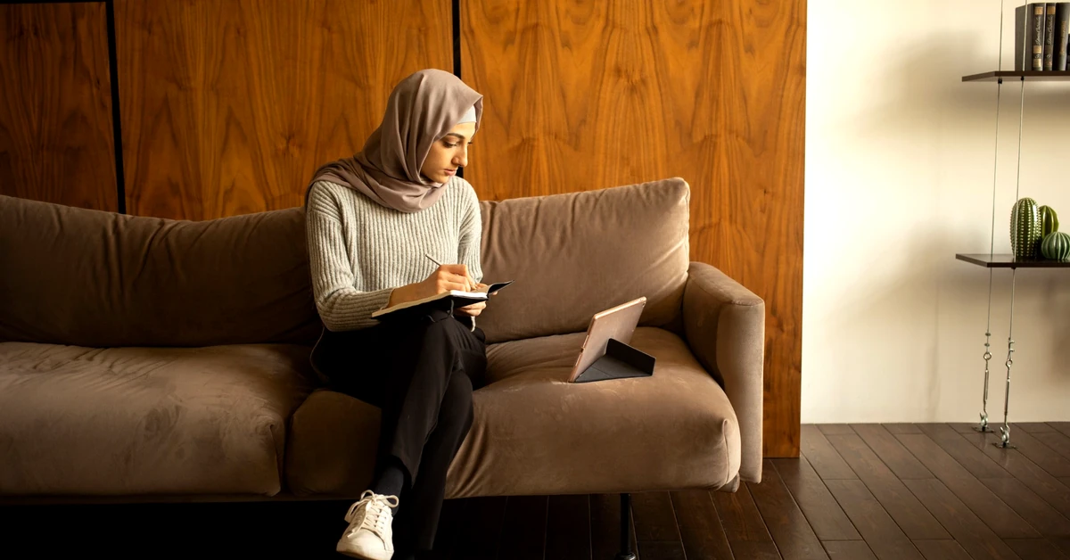 Woman taking notes while using a tablet to learn from educational content during an email welcome sequence