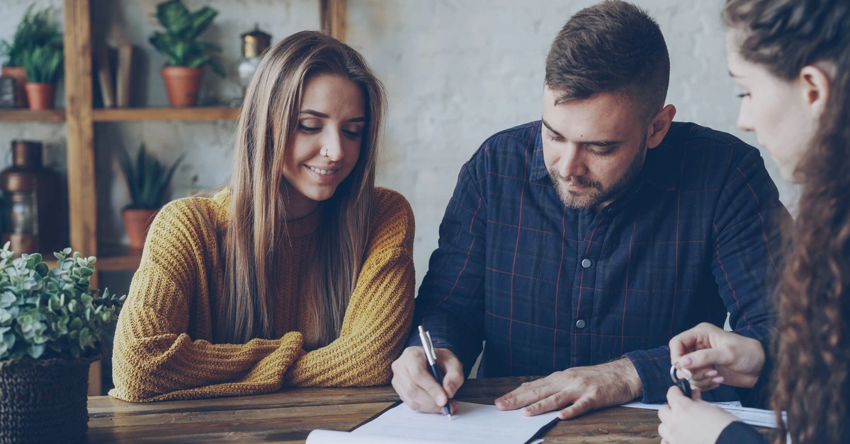 Three professionals reviewing and signing documents together, illustrating the importance of checking affiliate program terms before joining.