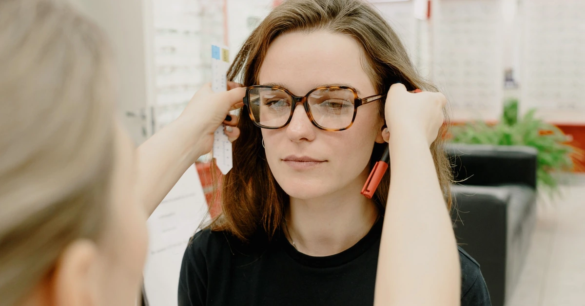 Optician fitting eyeglasses on a customer, illustrating the importance of deciding whether the ClickBank Profit Club is the right fit for your affiliate marketing goals.