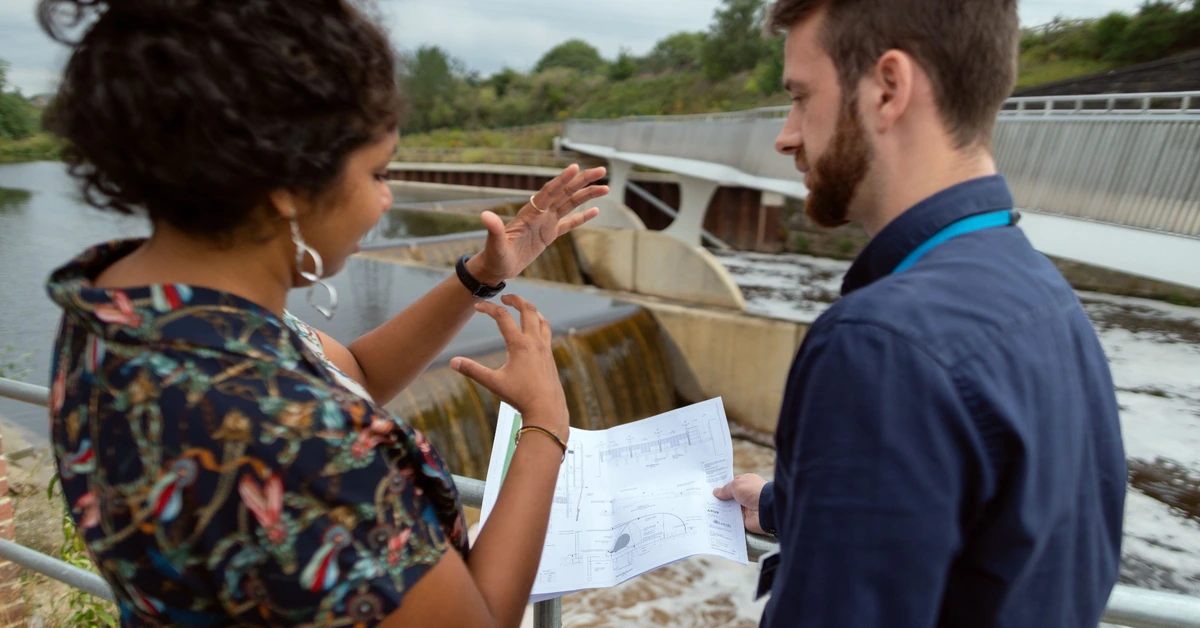 Two engineers reviewing plans together at a project site, illustrating how affiliates can compare tradeoffs between two ClickBank offers before choosing one.