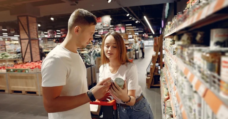 Two shoppers comparing products in a supermarket aisle, illustrating how affiliates can evaluate two ClickBank offers before choosing one to promote.