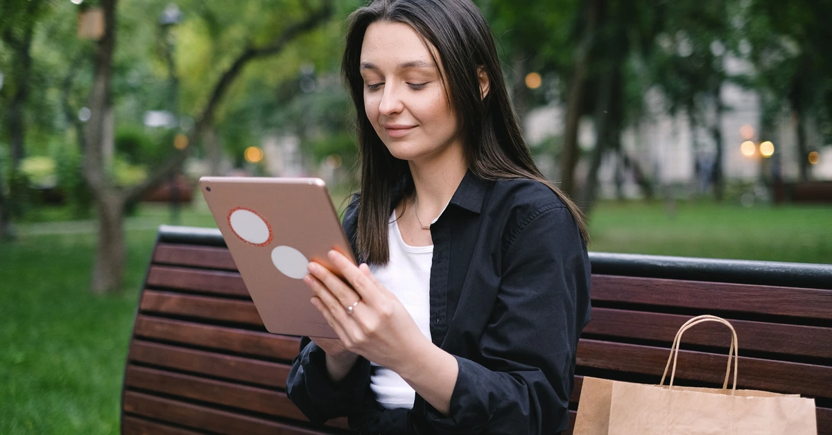 Woman using a tablet on a park bench, representing a reader encountering a blog post and email opt-in.