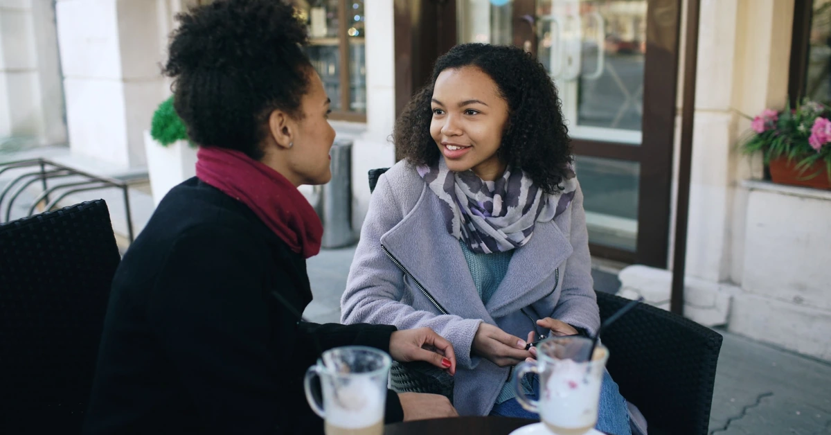 Two women having a friendly conversation over coffee, illustrating how affiliate email can build an ongoing relationship instead of pushing for an immediate sale.