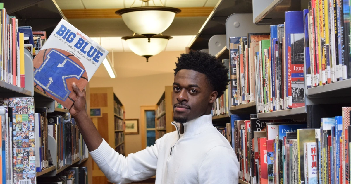 Man selecting one book from a library shelf, illustrating the value of giving an affiliate email one clear primary action.