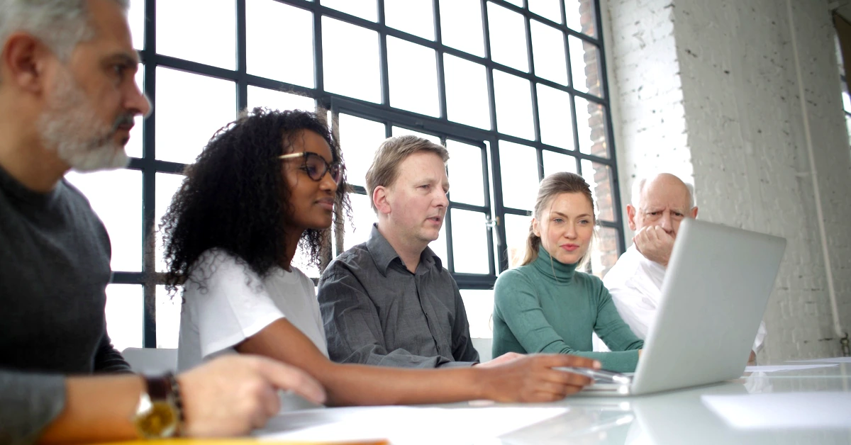 Diverse business team reviewing a laptop together while working through an affiliate marketing system