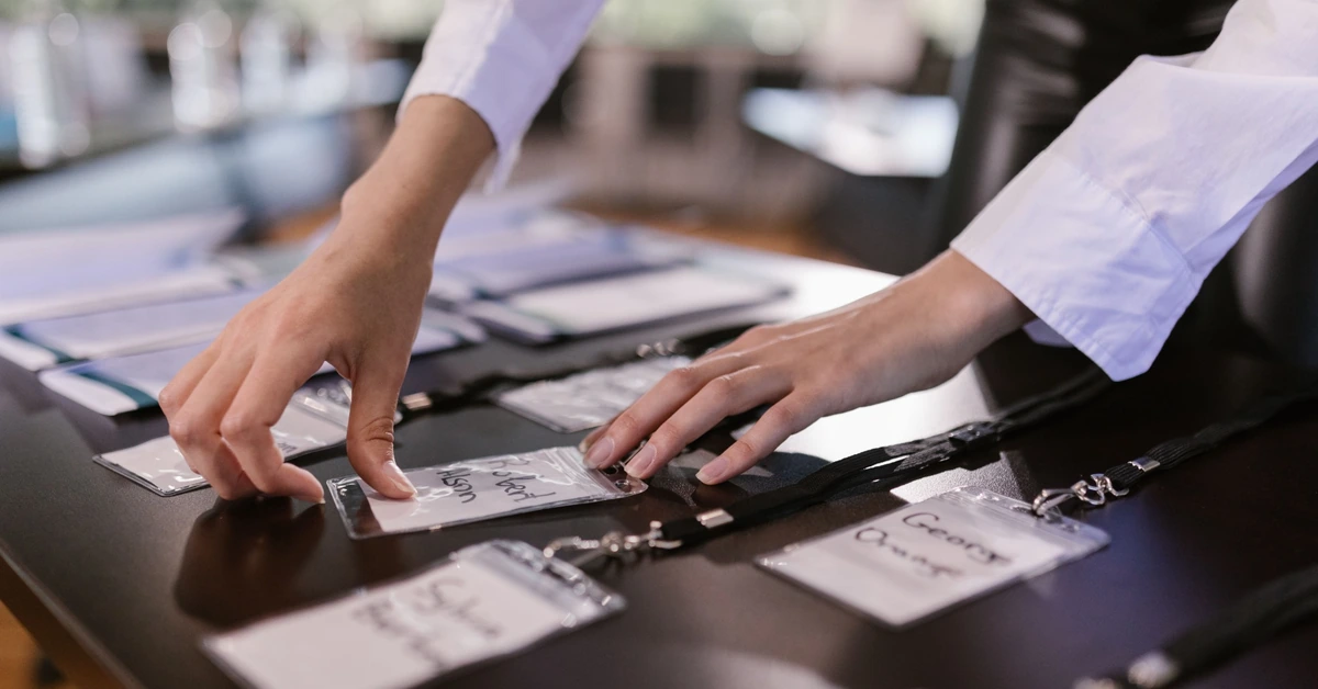 Hands arranging labeled name badges on a table, illustrating the importance of using clear and consistent affiliate campaign names.