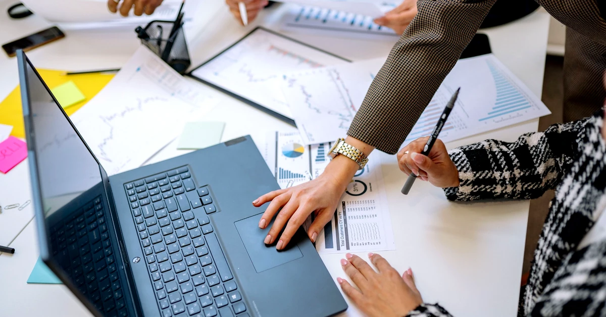 Marketing team reviewing charts and laptop data to evaluate the quality of affiliate clicks and campaign performance