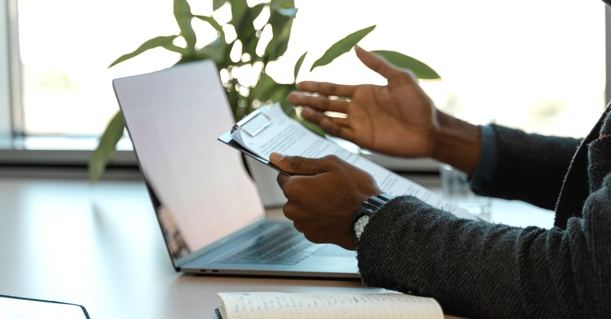 Affiliate marketer reviewing documents beside a laptop while evaluating whether a product is a good fit