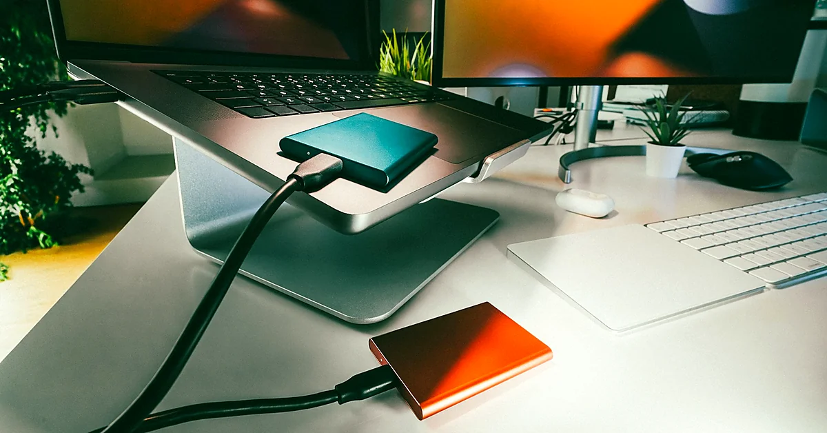 Two external storage drives connected by cables in a computer workspace, illustrating website backups and data recovery.
