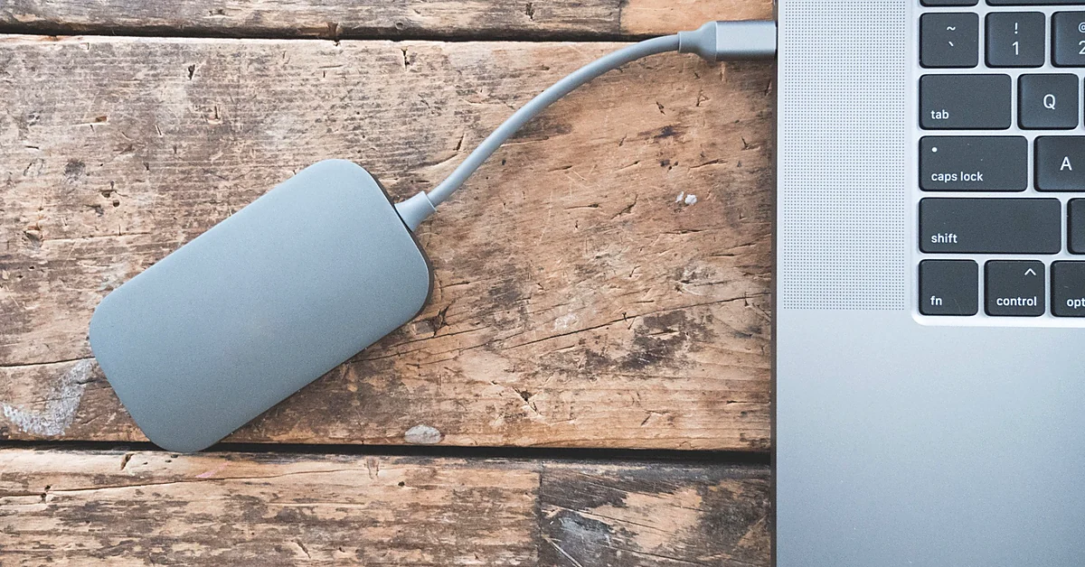 External backup drive connected to a laptop on a wooden desk, illustrating website backup protection before WordPress troubleshooting.